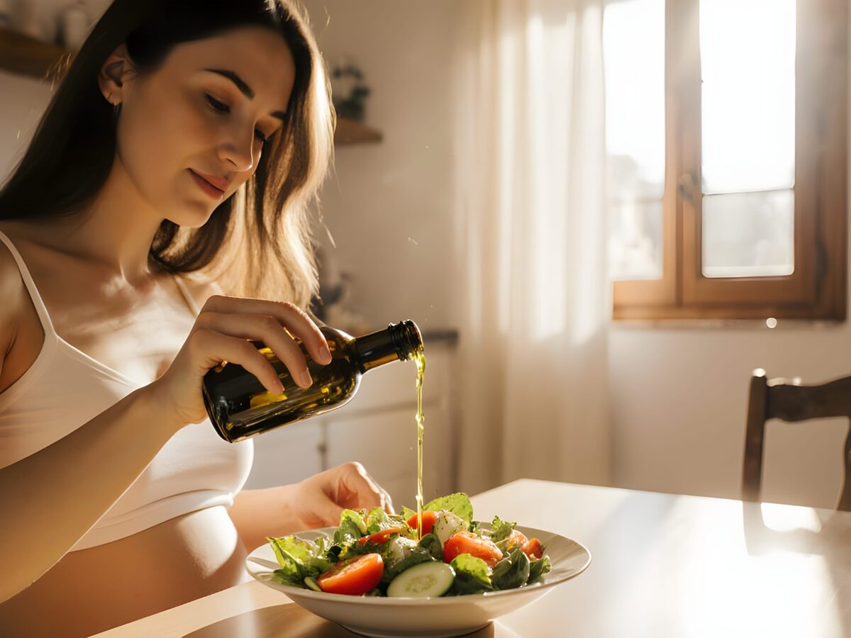 Kobieta w ciąży dodająca oliwę z oliwek do sałatki — cukrzyca ciążowa